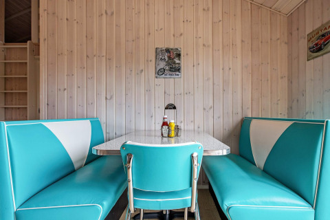 Retro eethoek met turquoise en witte zitbanken, houten wandbekleding en vintage decor in Sæby, Denemarken.