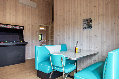 Retro eethoek met turquoise zitjes, arcadekast en houten muren in vakantiehuis in Sæby, Denemarken.