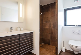Modern ingerichte badkamer in een vakantiehuis in Sæby, Denemarken, met inloopdouche, wastafel en wandtoilet.