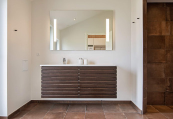 Modernes Badezimmer mit großem Spiegel, Holzwandwaschtisch und braunen Fliesen in Sæby-Ferienhaus.