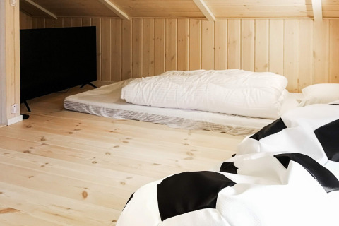 Slaaphoek met matras en tv op een zolderkamer van een vakantiehuis in Sæby, Denemarken.