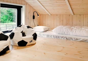 Chambre mezzanine dans maison de vacances 10 personnes à Sæby, Danemark, avec poufs football et matelas au sol.