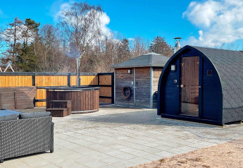 Area esterna della casa vacanze per 10 persone a Sæby, Danimarca, con sauna, vasca e salotto.