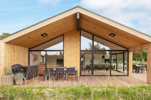 Moderne houten vakantiewoning in Sæby, Denemarken, met ruim terras, eethoek buiten en grote glaspartijen.