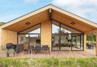 Modern houten vakantiehuis in Sæby, Denemarken, met groot terras, buiteneethoek en grote ramen.