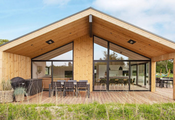 Moderne houten vakantiewoning in Sæby, Denemarken, met ruim terras, eethoek buiten en grote glaspartijen.