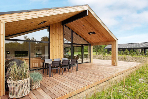 Lodge de vacances moderne à Sæby, Danemark, avec terrasse en bois et espace repas extérieur pour 10 personnes.