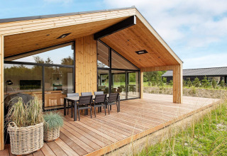 Modernes Ferienhaus in Sæby, Dänemark, mit Holzterrasse und Essbereich im Freien für 10 Personen.