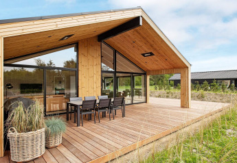 Modernes Ferienhaus in Sæby, Dänemark, mit Holzterrasse und Essbereich im Freien für 10 Personen.
