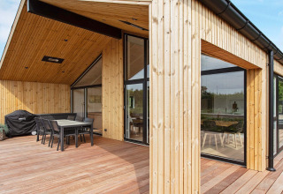 Alojamiento vacacional moderno en Sæby, Dinamarca, con terraza de madera y amplios ventanales.
