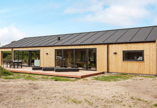 Modern vakantiehuis in Sæby, Denemarken, met houten gevel, groot terras en zwart dak voor 10 personen.