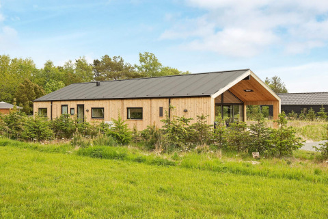 Vue extérieure d'une maison de vacances pour 10 personnes à Sæby au Danemark, entourée de verdure.
