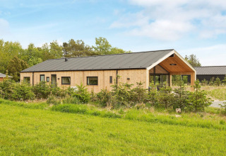 Außenansicht eines 10-Personen-Ferienhauses in Sæby, Dänemark, mit moderner Holzverkleidung im Grünen.
