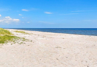 Zonnig uitzicht op een rustige zandstrand en blauwe zee bij Sæby, Denemarken, vanaf het vakantiehuis.