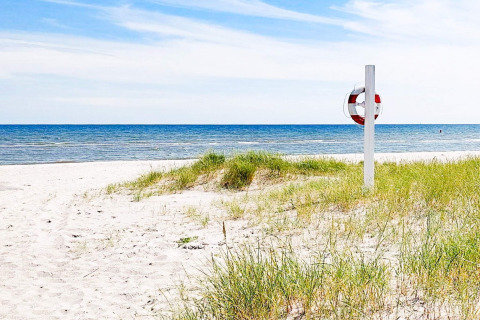 Zandstrand met grasduinen en reddingsboei vlakbij een 10-persoons vakantiehuis in Sæby, Denemarken.