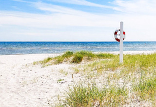 Sandstrand mit Dünen, Rettungsring und Meerblick, nahe einem 10-Personen-Ferienhaus in Sæby, Dänemark.