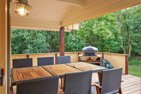 Veranda coperta al Cozy Coastal Cottage Retreat in Danimarca con tavolo, sedie e barbecue esterno.