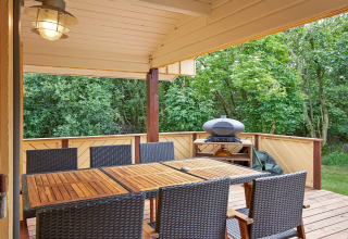 Veranda coperta al Cozy Coastal Cottage Retreat in Danimarca con tavolo, sedie e barbecue esterno.