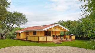 Charmant cottage côtier jaune avec terrasse en bois et toit rouge au Cozy Coastal Cottage Retreat.