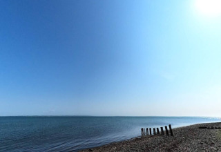 Immagine della tranquilla costa presso Cozy Coastal Cottage Retreat, Danimarca, con mare blu e cielo sereno.