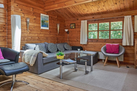Accogliente soggiorno con pareti in legno, ampia finestra e arredi moderni nel Cozy Coastal Cottage Retreat, Danimarca.
