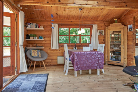 Interno accogliente di cottage danese con tavolo da pranzo, sedie, vetrina e luce naturale dalle finestre.