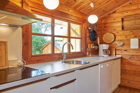 Lyst køkken i træ med store vinduer, moderne faciliteter og udsigt til natur ved Cozy Coastal Cottage Retreat.