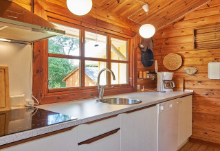 Lyst køkken i træ med store vinduer, moderne faciliteter og udsigt til natur ved Cozy Coastal Cottage Retreat.