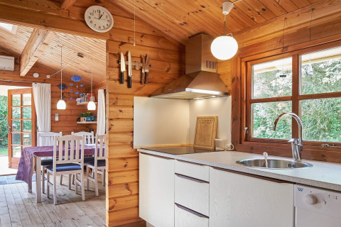 Knusse keuken en eetruimte met houten muren bij Cozy Coastal Cottage Retreat in Denemarken, daglicht aanwezig.