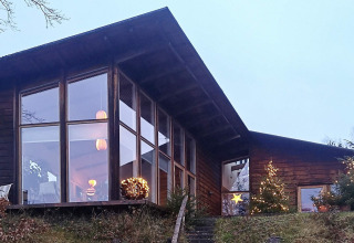 Modernes Ferienhaus in Bryrup, Dänemark, mit großen Fenstern und festlichen Lichtern am Abend.