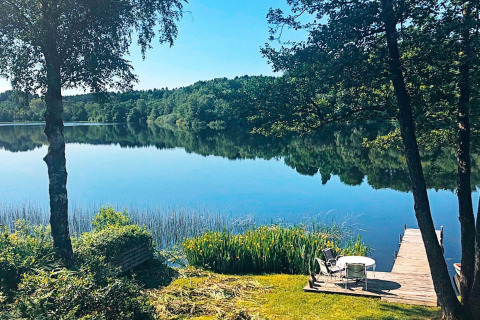 Vista di un lago tranquillo e foresta dal molo della casa vacanze per 6 persone a Bryrup, Danimarca.