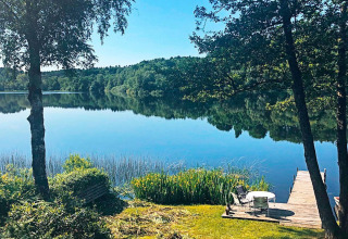 Udsigt over en rolig sø og skov fra en terrasse ved 6 personers feriehus i Bryrup, Danmark.
