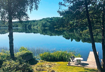 Vue sur un lac paisible et une forêt depuis le ponton du gîte 6 personnes à Bryrup, Danemark.