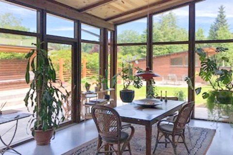 Sala da pranzo luminosa in casa vacanze per 6 persone a Bryrup, Danimarca, con grandi finestre e piante.