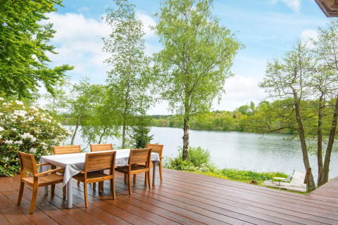 Wooden deck with dining table and lake view at 6 person holiday home in Bryrup, Denmark