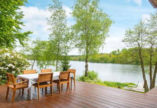 Terrazza in legno con tavolo da pranzo e vista lago nella casa vacanze per 6 persone a Bryrup, Danimarca