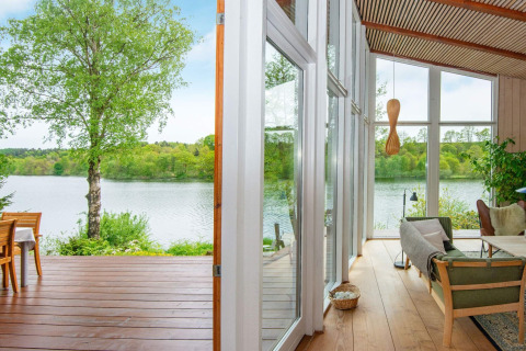 Vista da una casa vacanze a Bryrup, Danimarca, con terrazza lago e ambiente interno moderno.
