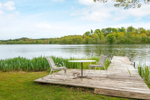 Muelle de madera con mesa y sillas junto al lago en casa de vacaciones para 6 personas en Bryrup, Dinamarca.