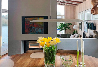 Salle à manger dans une maison de vacances à Bryrup, Danemark, avec tulipes jaunes et vue sur le lac.