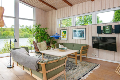 Soggiorno luminoso e moderno in una casa vacanze a Bryrup, Danimarca, con ampie finestre e verde vista.