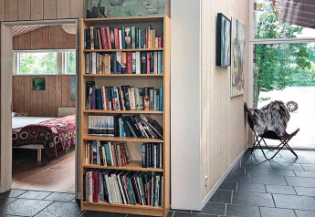 Cozy holiday lodge in Bryrup, Denmark, featuring a bookshelf, bedroom view, and window to beautiful nature.
