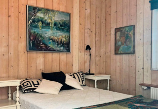 Camera da letto in una casa vacanze a Bryrup, Danimarca, con pannelli in legno, quadri, letto e comodini.