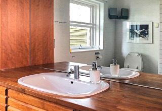 Bathroom with wood countertop, sink, and mirror in a 6-person holiday home in Bryrup, Denmark.