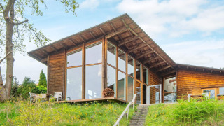 Vista exterior de una casa de vacaciones para 6 personas en Bryrup con ventanales y entorno natural verde.