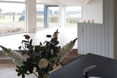 Vista interna di casa vacanze per 8 persone a Sydals, Danimarca, con fiori, candele e grandi finestre.