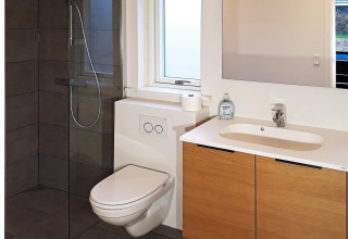 Moderne badkamer in vakantieverblijf in Sydals, Denemarken met wc, douche, lavabo en spiegel.