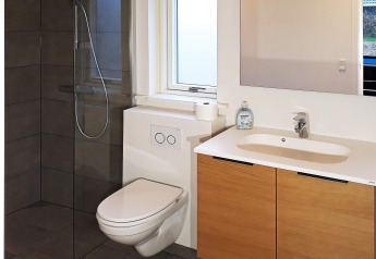 Moderne badkamer in vakantiehuis in Sydals, Denemarken met toilet, douche, wastafel en spiegel.