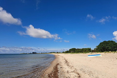 Sandstrand med blå himmel og enkelte skyer nær 8 personers feriehus i Sydals, Danmark.