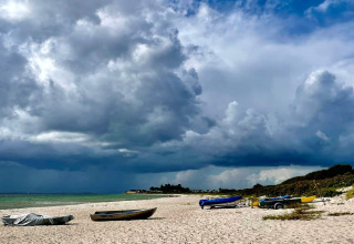 Playa con botes bajo nubes de tormenta cerca de la casa de vacaciones para 8 personas en Sydals, Dinamarca.