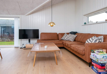 Salon d'une maison de vacances pour 8 personnes à Sydals, Danemark, avec canapé brun, télévision et jeux de société.